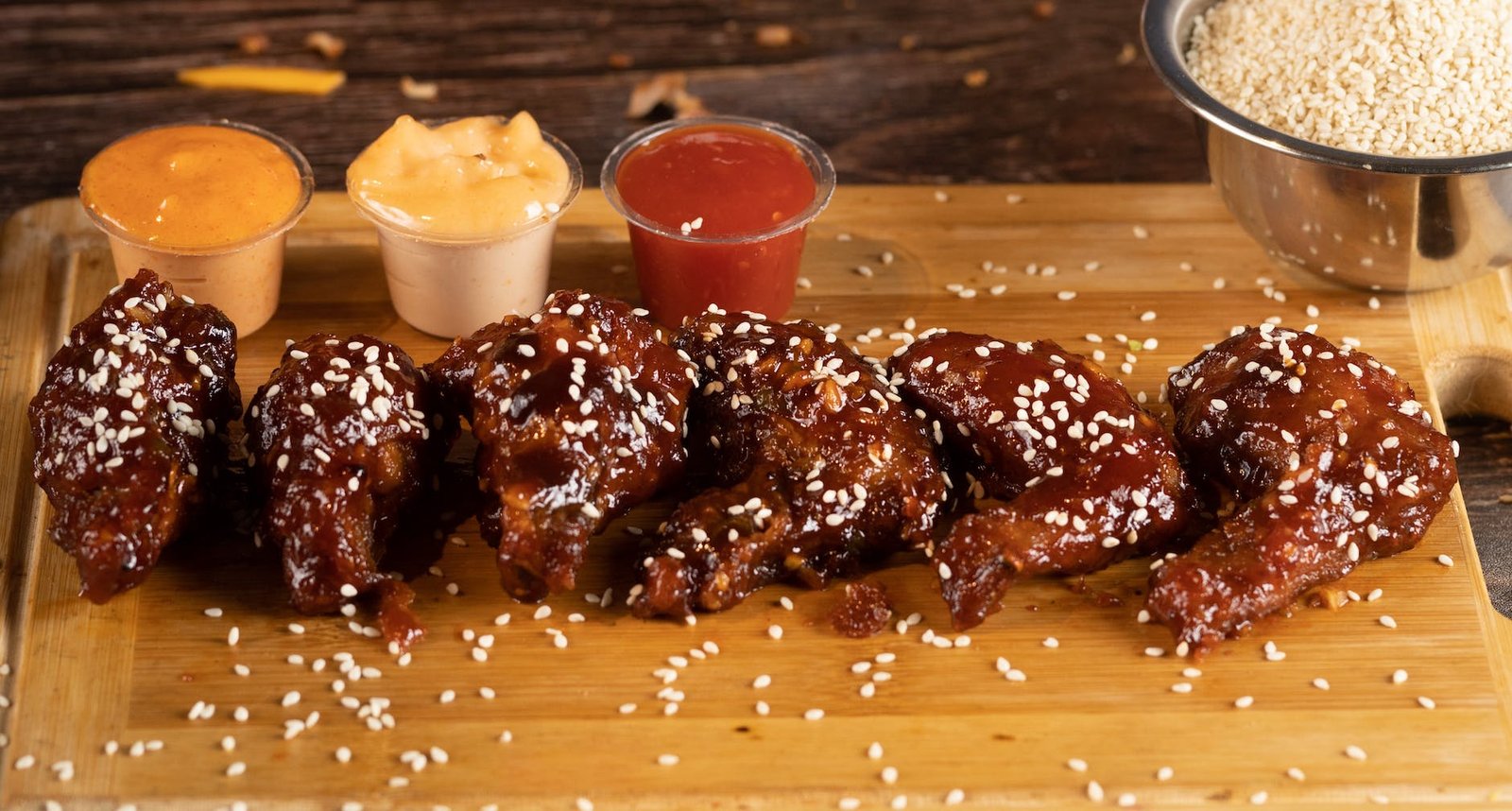 buffalo wings with sesame seeds and dips on plastic containers